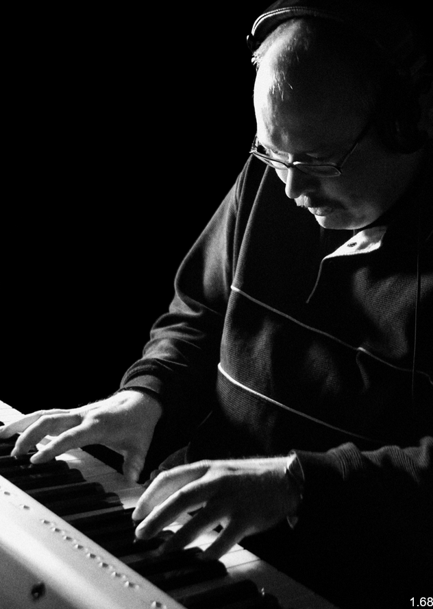 KI generiert: Ein Mann mit Kopfhörern spielt konzentriert auf einem Keyboard. Die Szene ist in Schwarz-Weiß gehalten und der Fokus liegt auf dem spielenden Musiker.