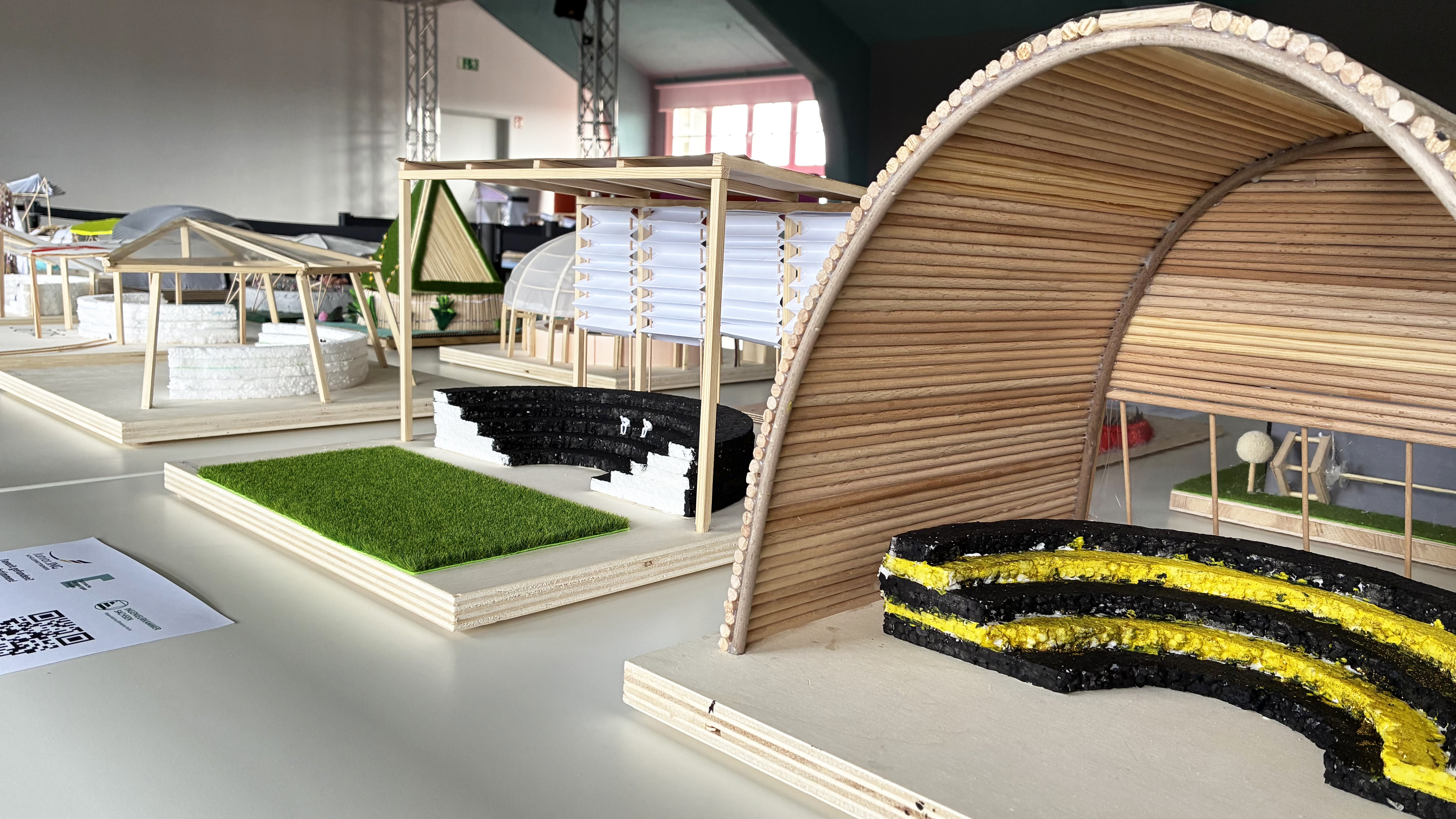 AI generated: The image shows a series of architectural models built from different materials and displayed on tables in an exhibition space. Each model has different design features and structures that represent a variety of architectural styles and concepts.