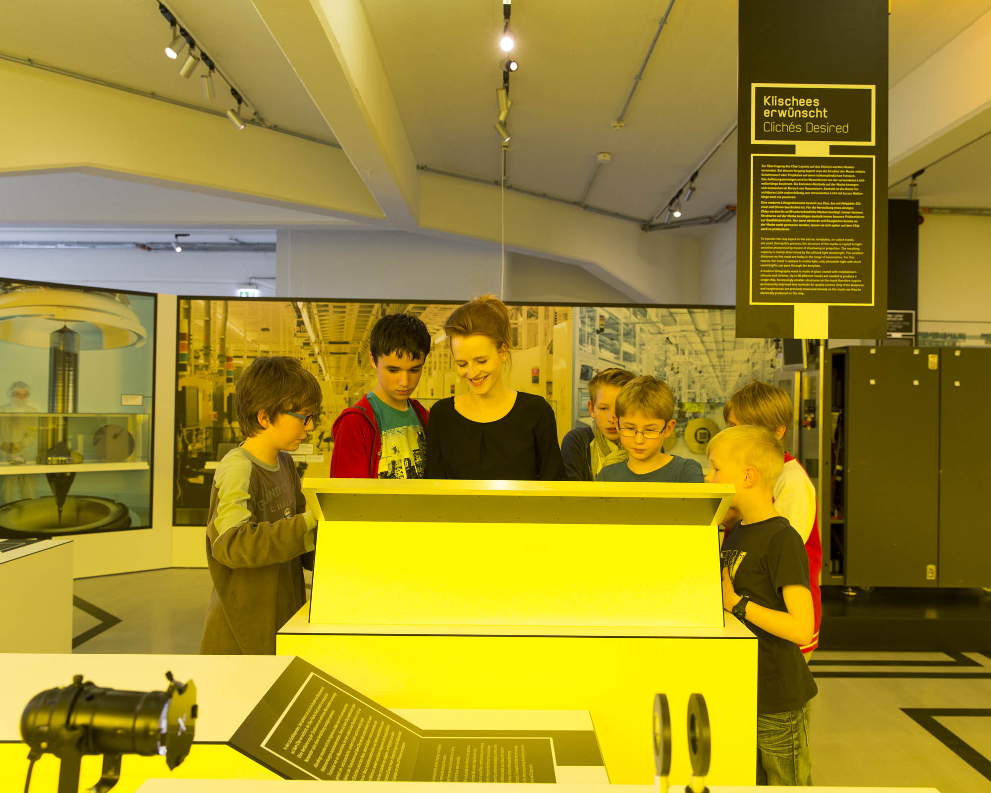 KI generiert: Das Bild zeigt eine Gruppe von Kindern und eine Frau, die gemeinsam eine interaktive Ausstellung in einem Museum betrachten. Sie scheinen intensiv in das Display vertieft zu sein.