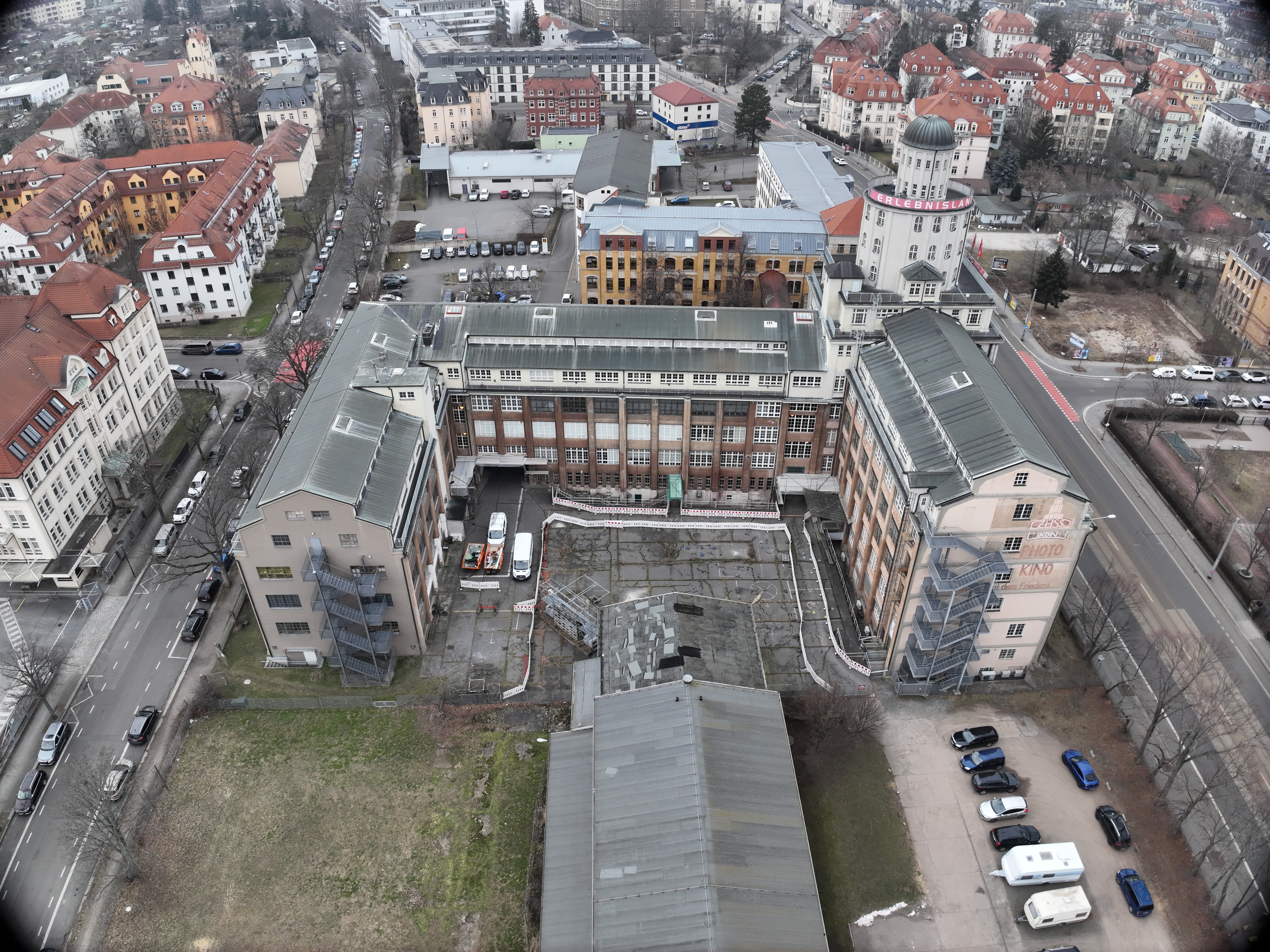 AI generated: The image shows an aerial view of an urban area with a large historic building complex in the foreground, surrounded by streets and residential buildings. In the background you can see another development with houses lined up close together.