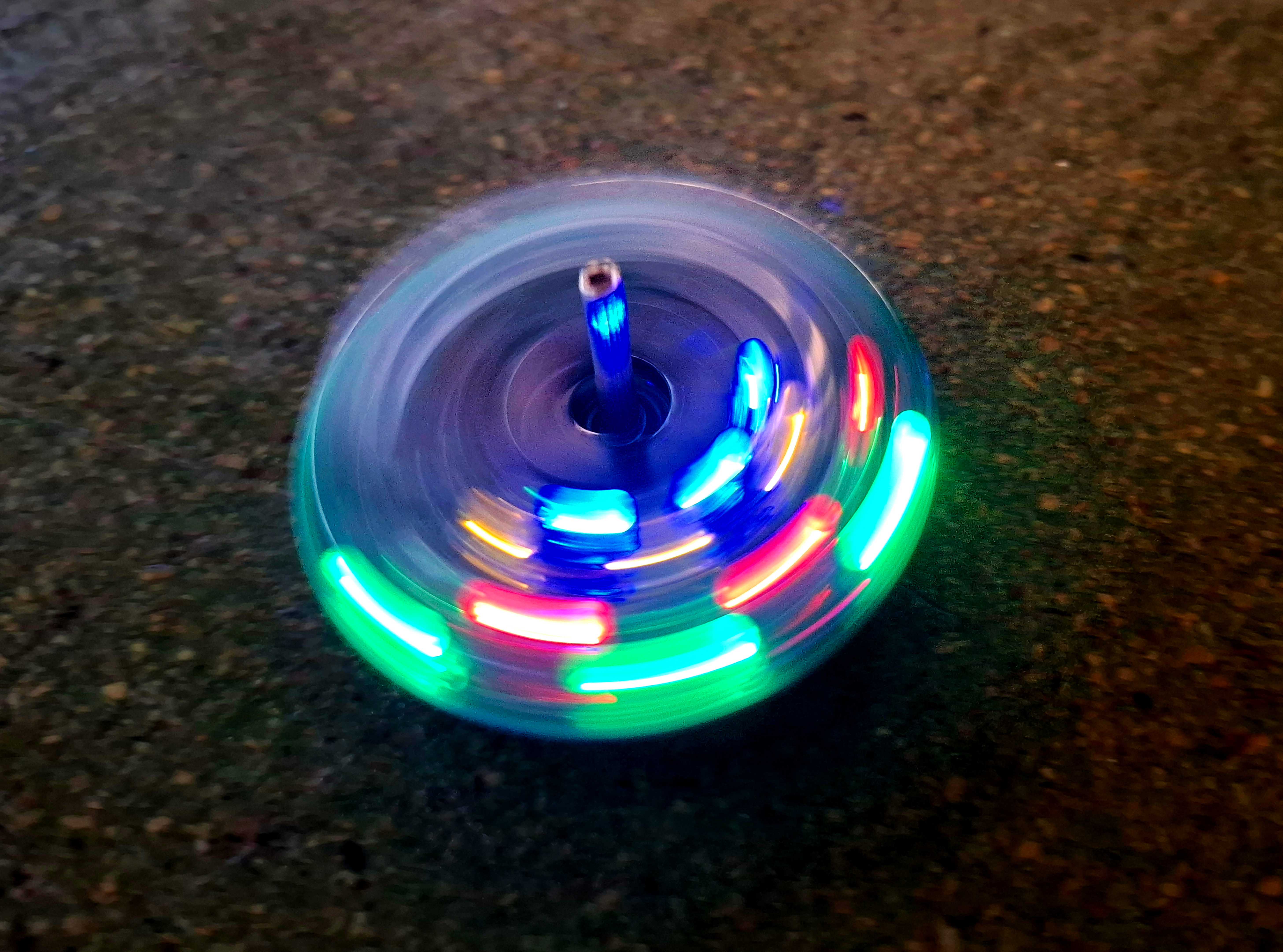 AI generated: The image shows a spinning top with glowing LED lights in different colours. The spinning top creates a colourful lighting effect as it rotates.