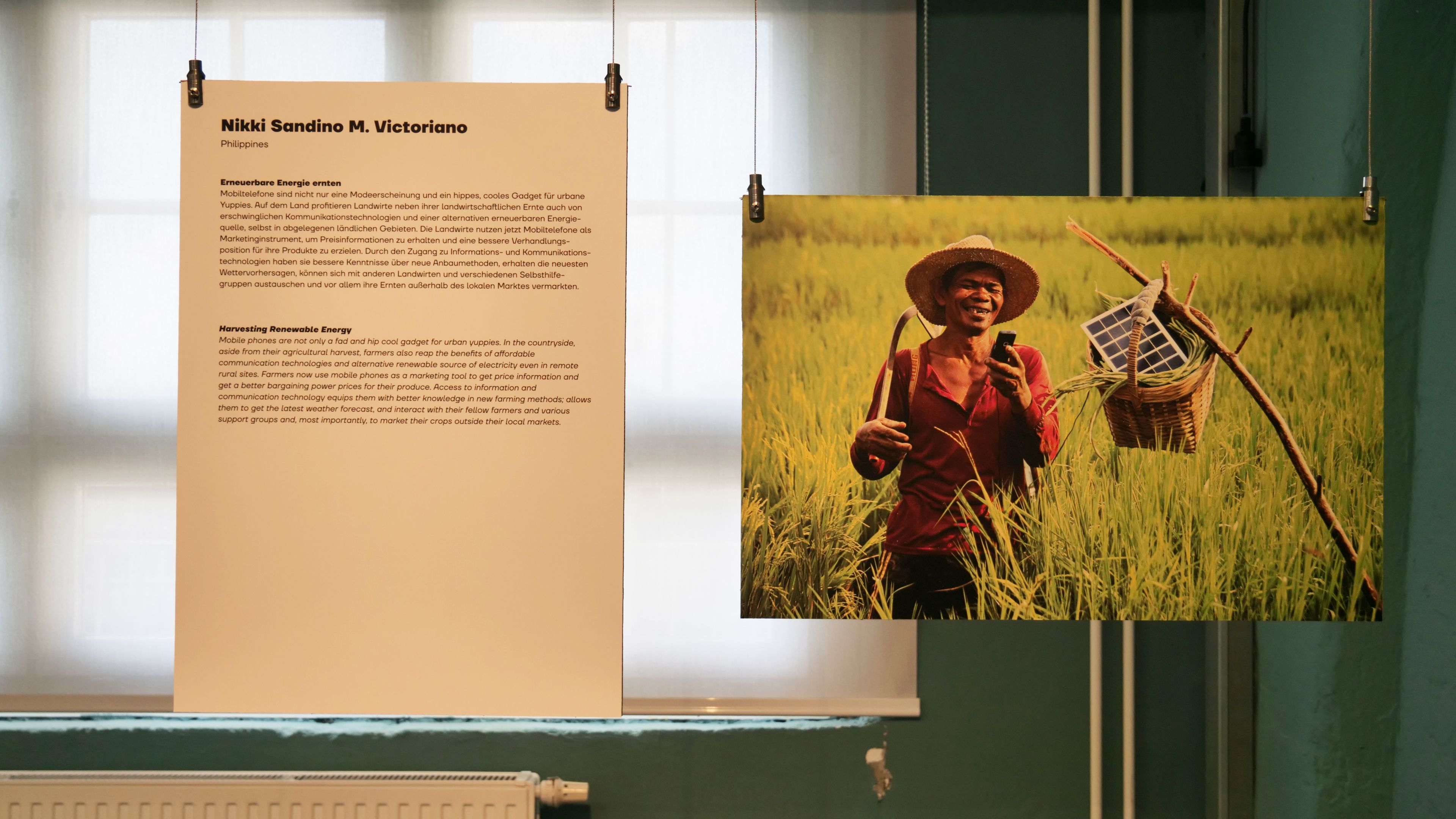 KI generiert: Das Bild zeigt eine Ausstellung mit zwei Tafeln: links eine Texttafel, die sich mit nachhaltiger Energie beschäftigt, und rechts ein Foto eines lächelnden Mannes auf einem Feld, der einen Korb mit Solarpanelen trägt.