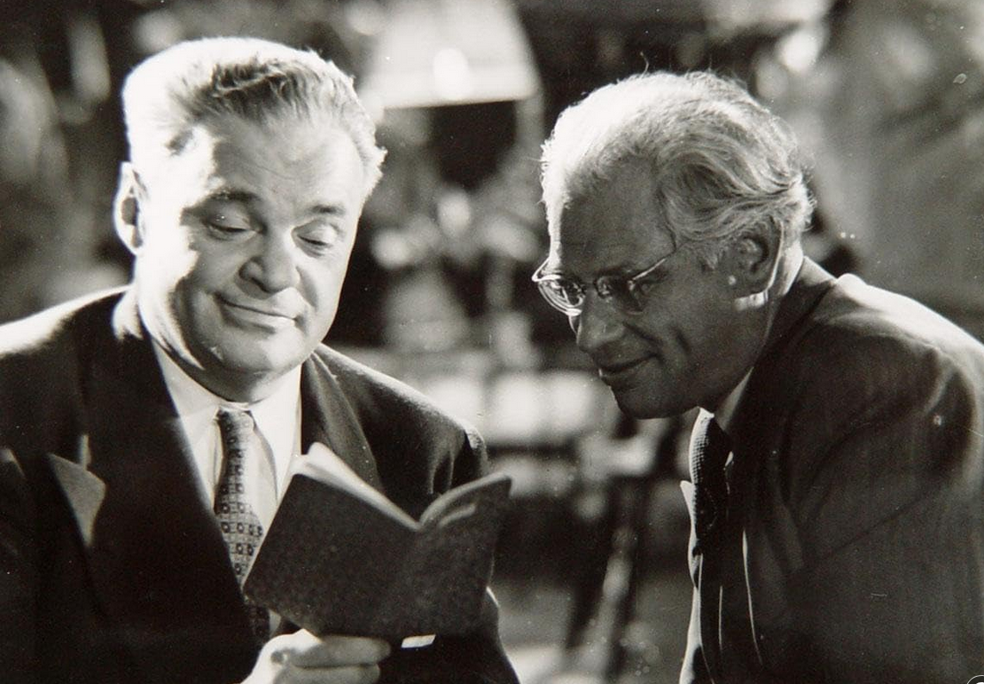 KI generiert: Zwei ältere Männer in Anzügen schauen sich gemeinsam ein kleines Buch an. Sie scheinen konzentriert und interessiert zu sein.