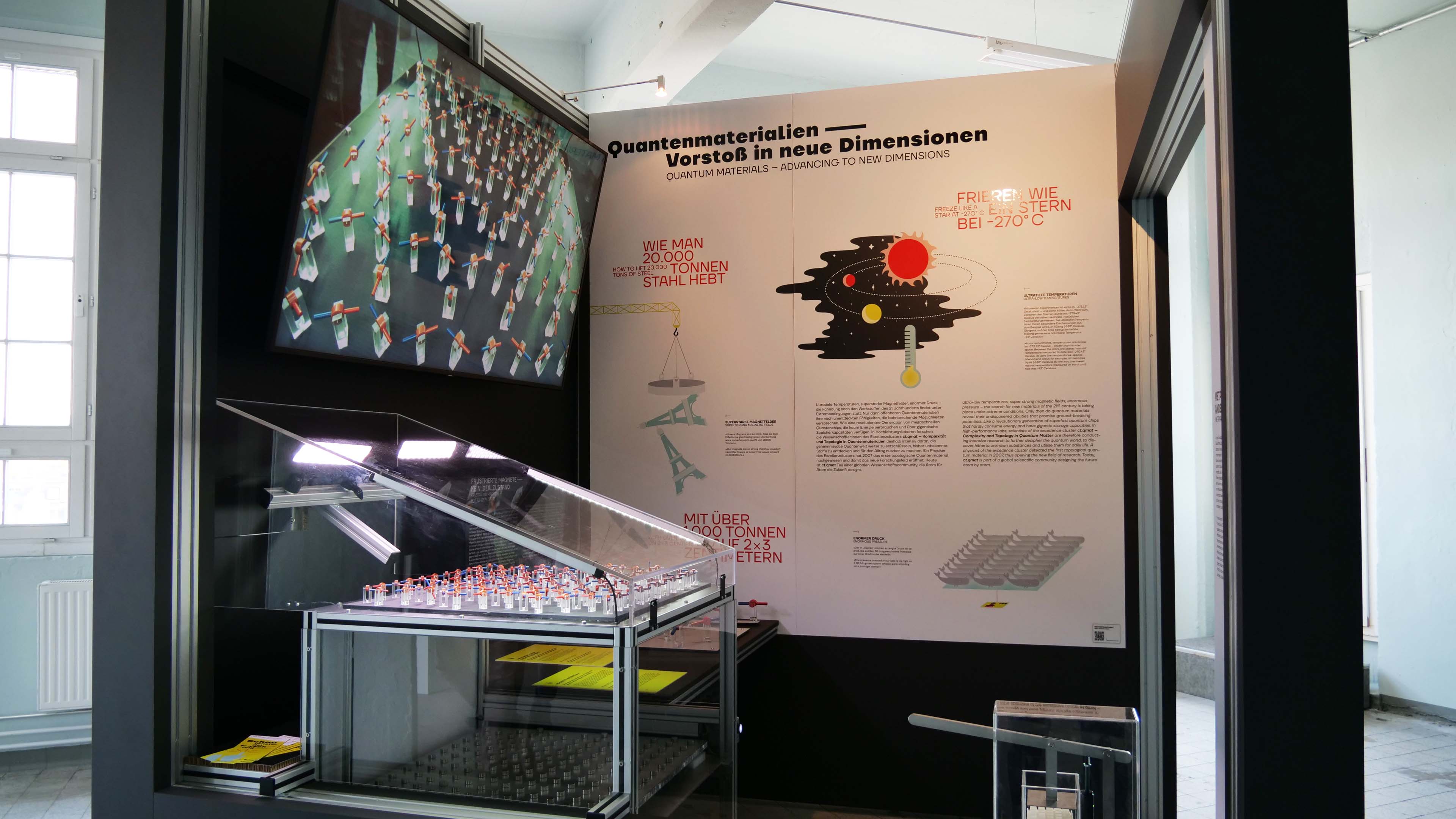 KI generiert: Das Bild zeigt eine Ausstellung über Quantenmaterialien mit verschiedenen Schautafeln und Modellen. Hauptinhalt ist die Darstellung neuer Dimensionen durch fortschrittliche Quantenmaterialien.